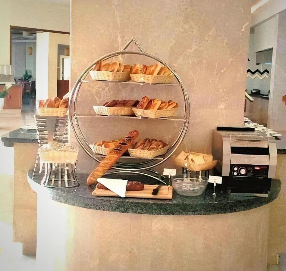 Tolip Resort El Galala Majestic Ain Sukhna Exterior foto The photo shows a display of various types of bread and pastries arranged on a countertop. There are several baskets stacked on a circular stand, filled with different baked goods like croissants and rolls. A long baguette is placed horizontally on a